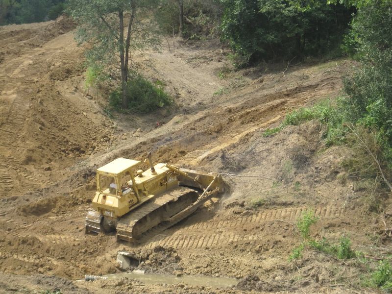 Yellow GCI dozer clearing and shaping a wooded hillside