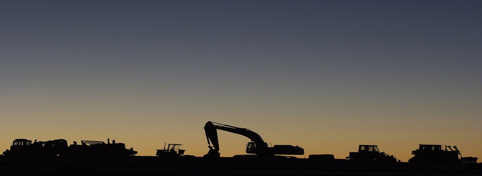 Granger Construction's excavator, dozers and loaders silhouetted at sunset